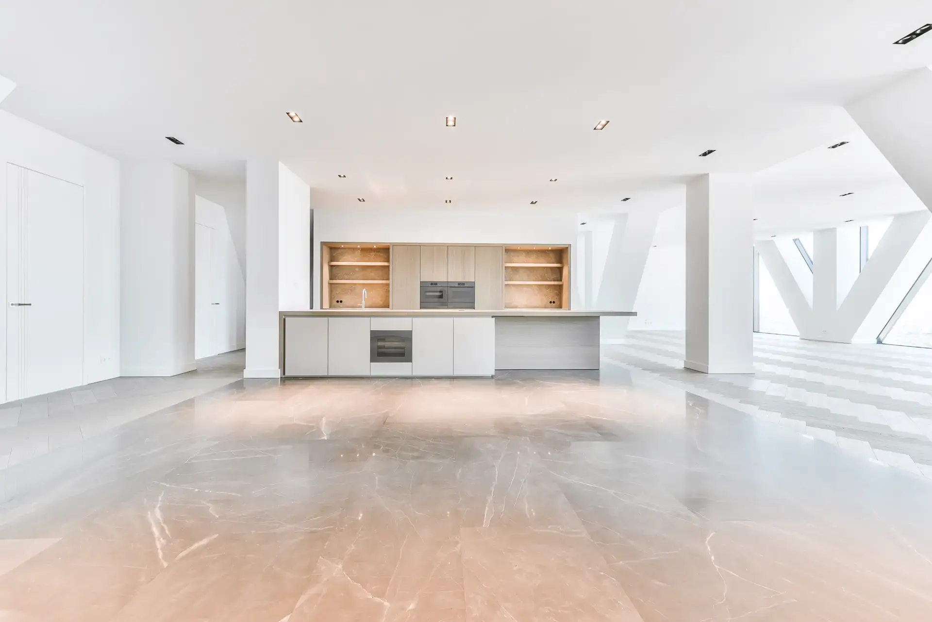 Elegant og moderne køkken i et lyst, åbent rum med store vinduer og minimalistisk design.