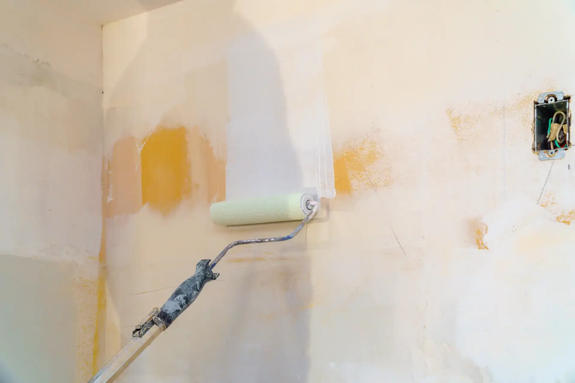 Malerarbejde med rulle på væg under renovering.